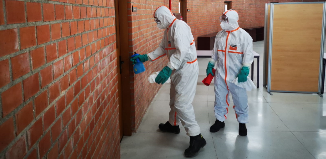 dos profesionales con protección realizando limpieza en un edificio