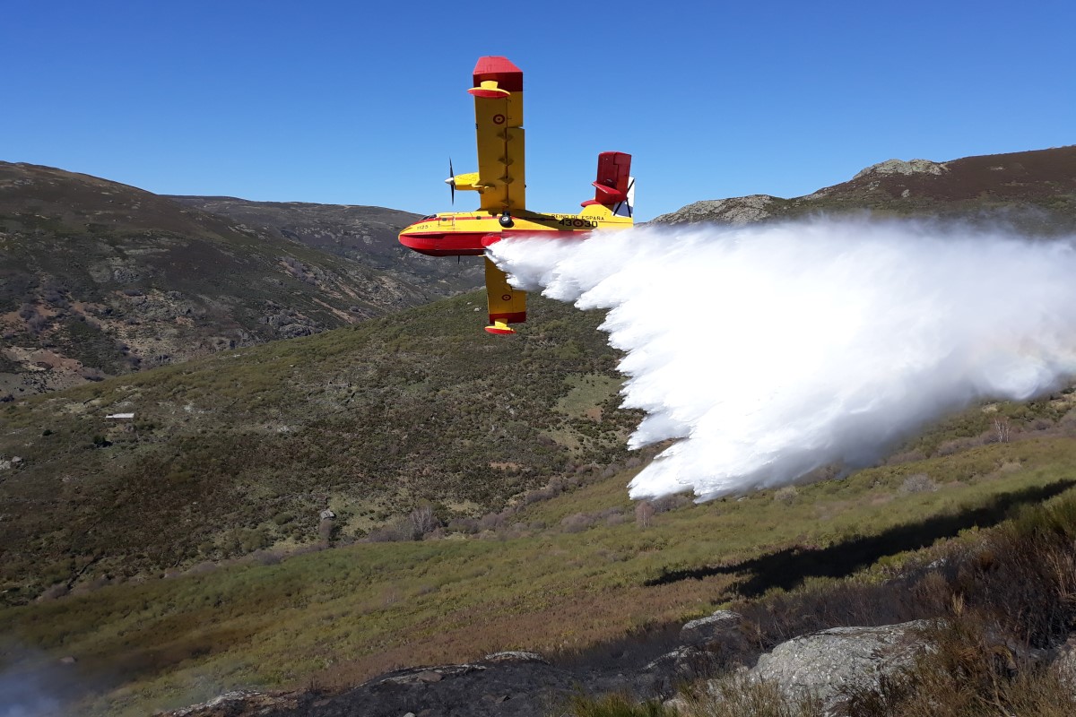 Hidroavión descargando agua sobre la ladera de una montaña