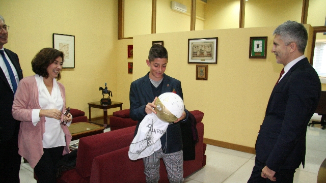 el joven Cristian Fernández recibiendo un regalo por parte de Grande-Marlaska