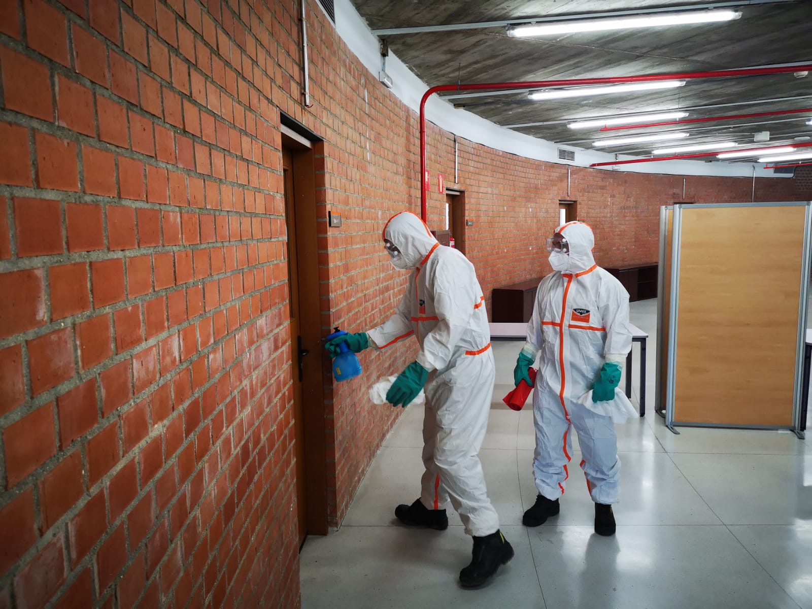 dos profesionales con protección realizando limpieza en un edificio
